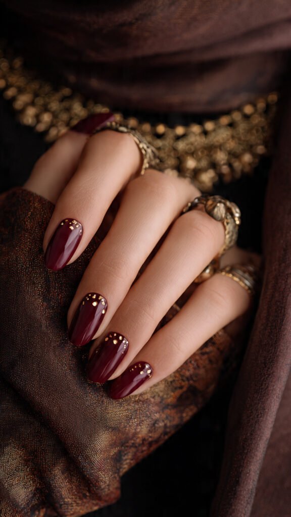 deep-burgundy-nails-with-gold-foil-accents-and-tin